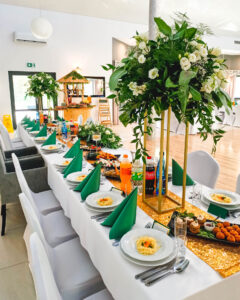 stół z białym obrusem, na którym stoi zastawa weselna oraz kwiaty